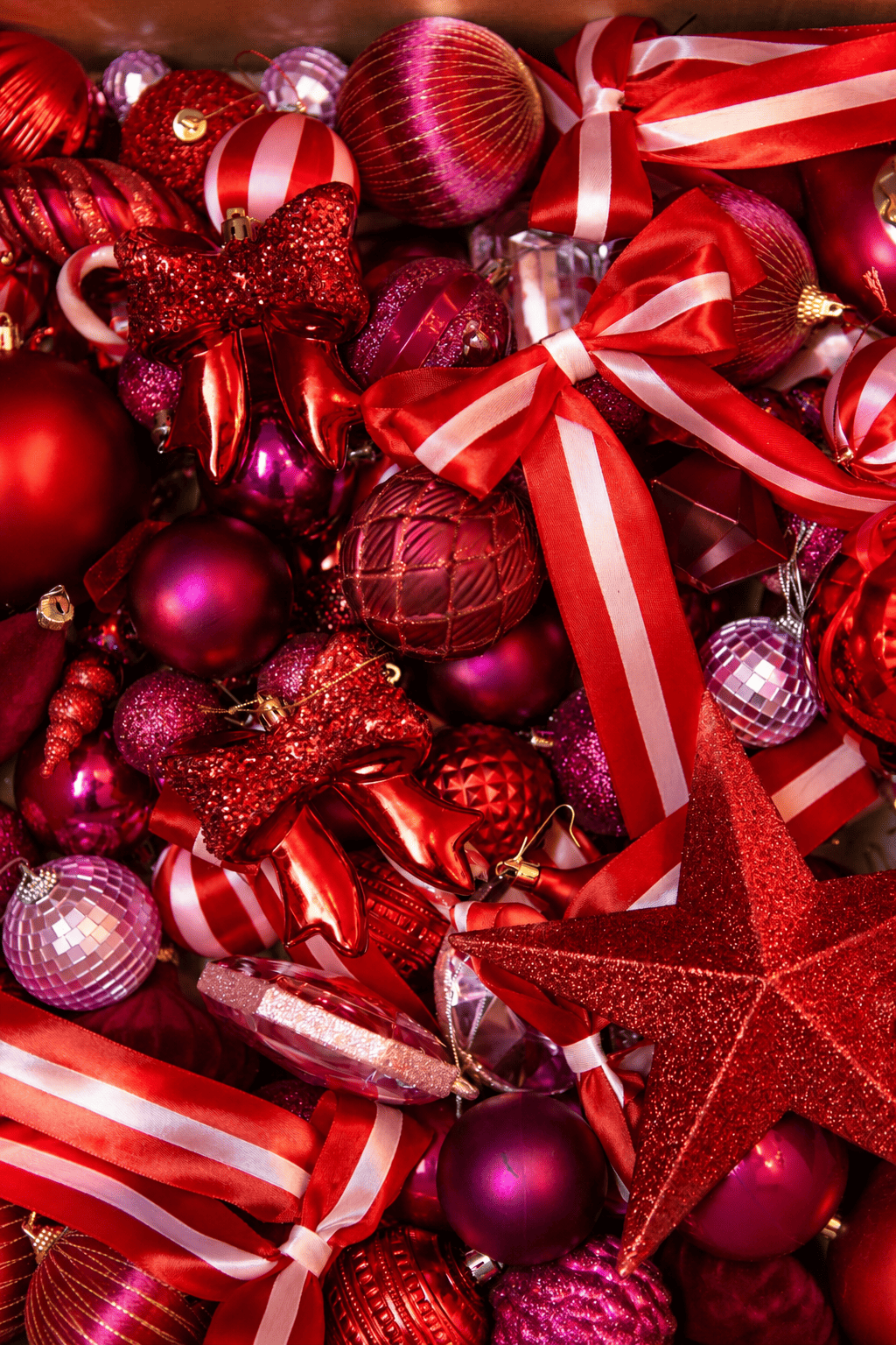 Overzicht van het kerstdecoratiepakket A Jolly Christmas met rode, roze en paarse kerstballen, rood-wit gestreepte strikken, glittersterren en feestelijke kersthangers.