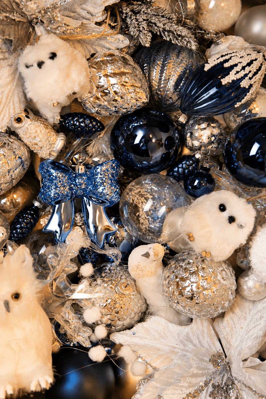 Overzicht van het kerstdecoratiepakket Snow White Christmas met donkerblauwe en zilveren kerstballen, witte uiltjes, blauwe glitterstrikken, dennenappels en winterse kerstversiering.
