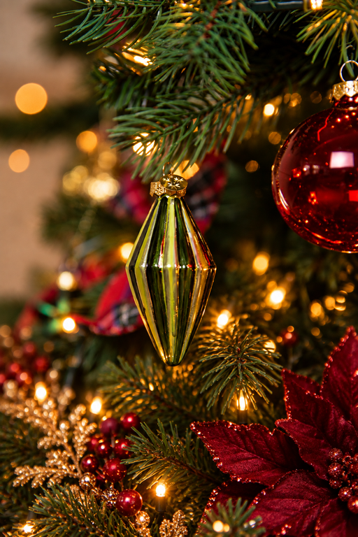 Detail van A Christmas Heritage kerstboomversiering met een langwerpige gouden kersthanger, rode kerstbal, rode kerstbloem en warme kerstverlichting.