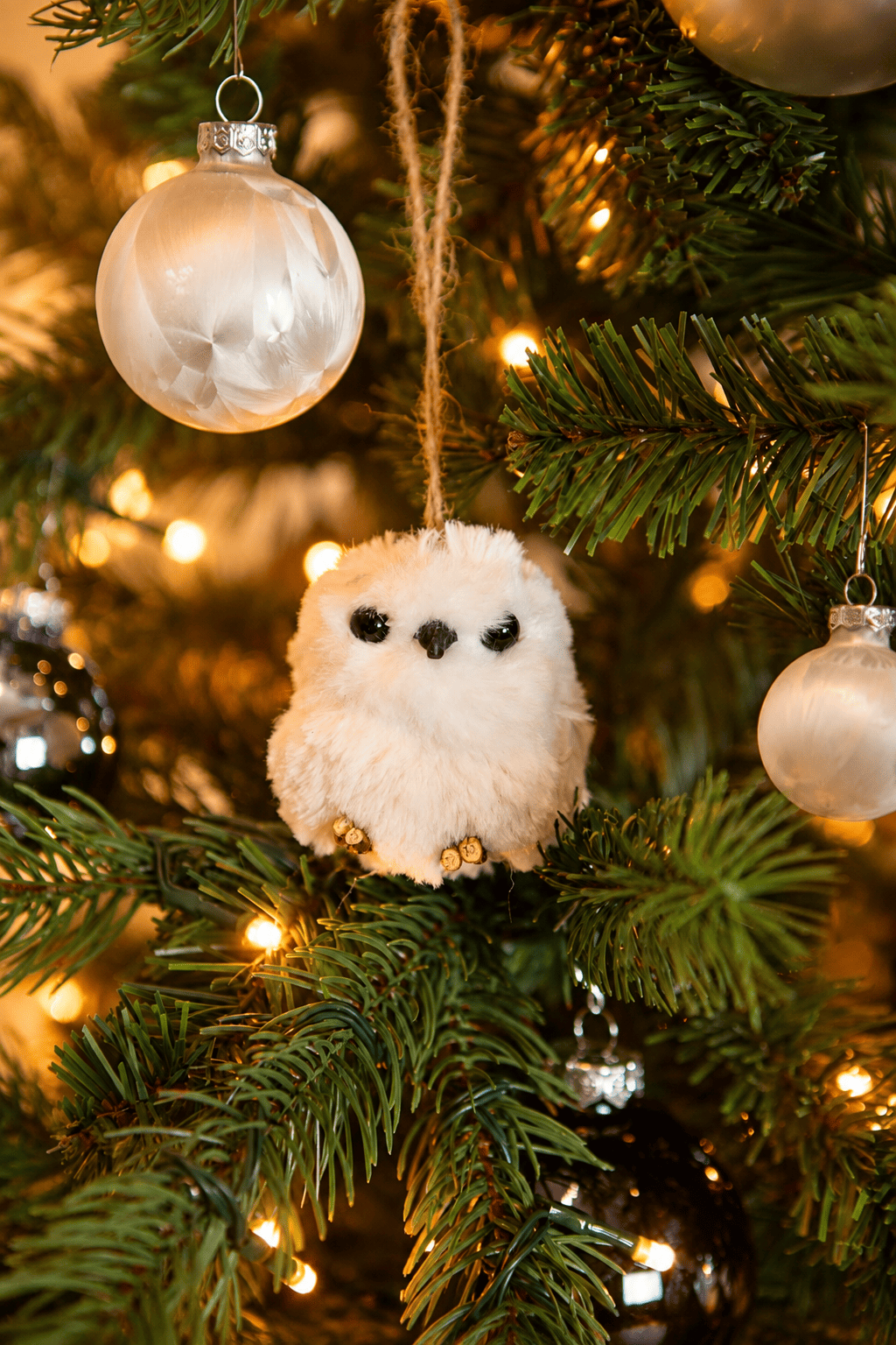 Detail van Snow White Christmas kerstboomversiering met een witte uilenhanger, parelmoerkleurige kerstballen en warme kerstverlichting.